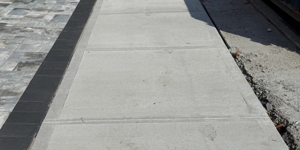 Contractor replacing damaged sidewalk slabs in Brooklyn NY with new concrete installation.